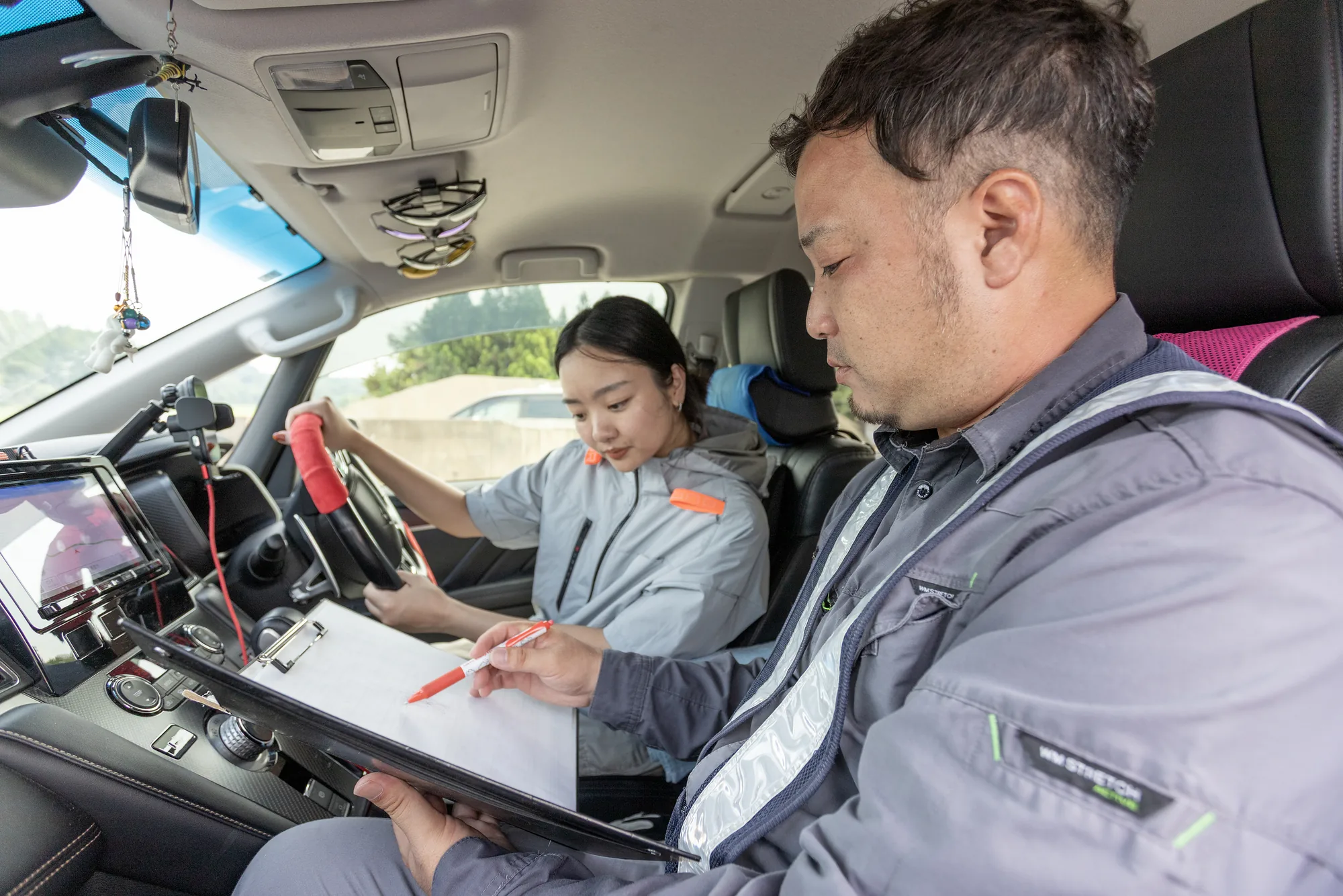 代表から特殊車両誘導の研修を受ける若手のドライバー