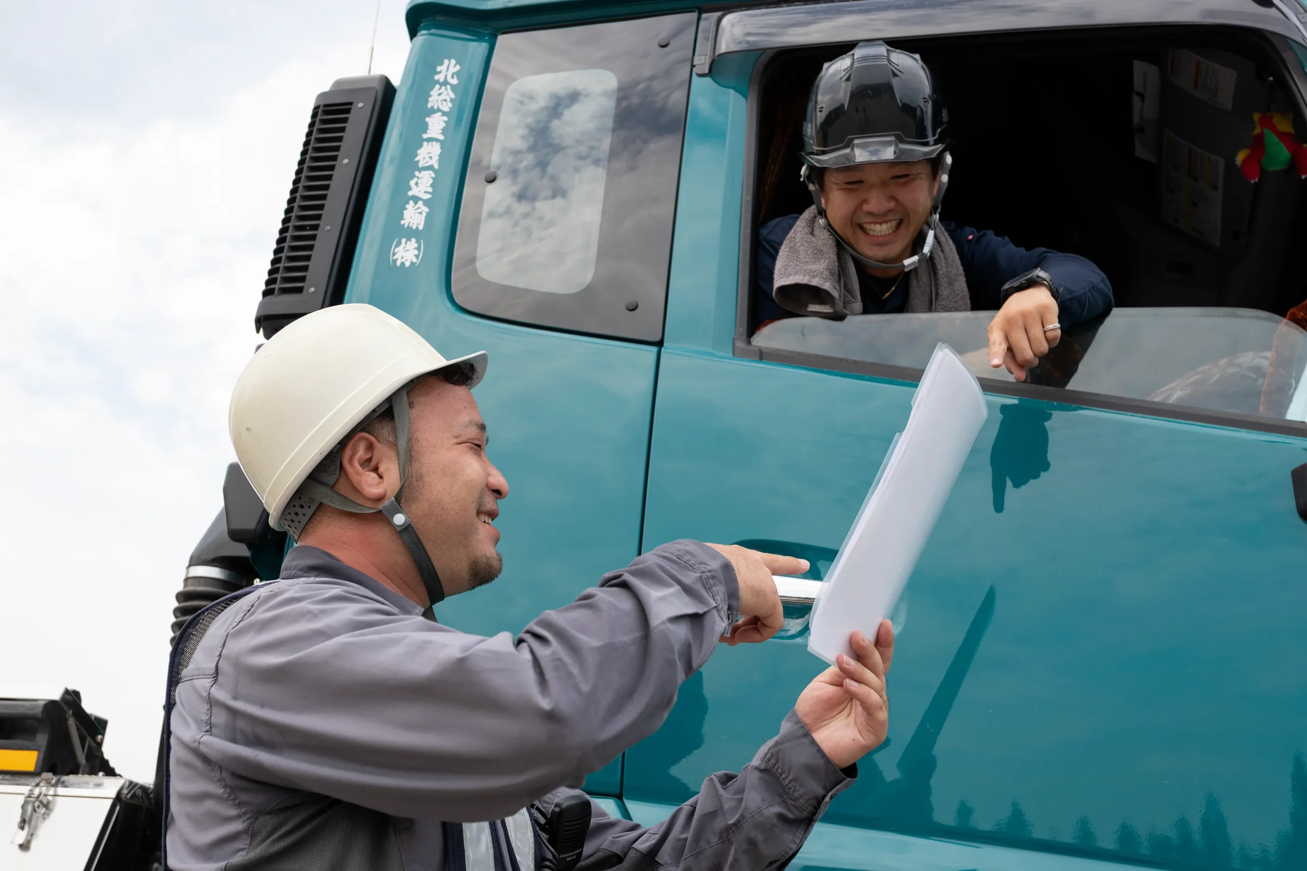 トレーラーの運転集と打ち合わせをする誘導員